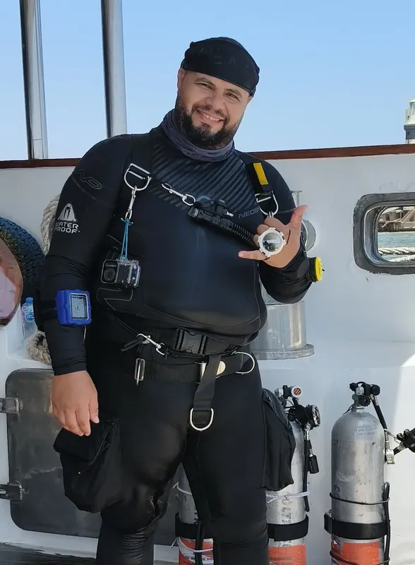 Plongeur souriant sur un bateau avec son équipement complet