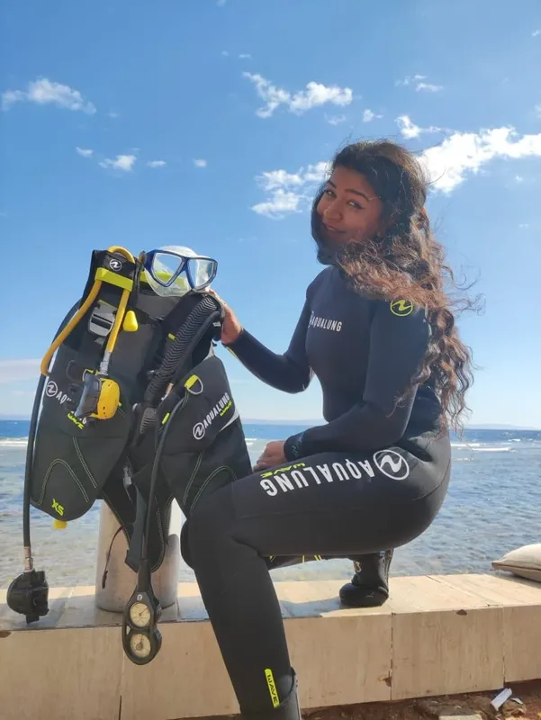 Plongeuse souriante avec son équipement complet près d'une rambarde