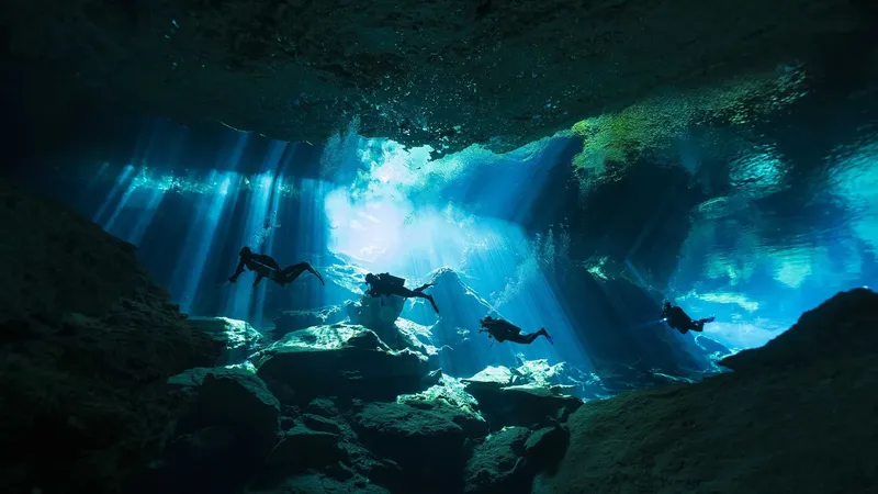 Plongeurs explorant une grotte sous-marine éclairée par des rayons de soleil