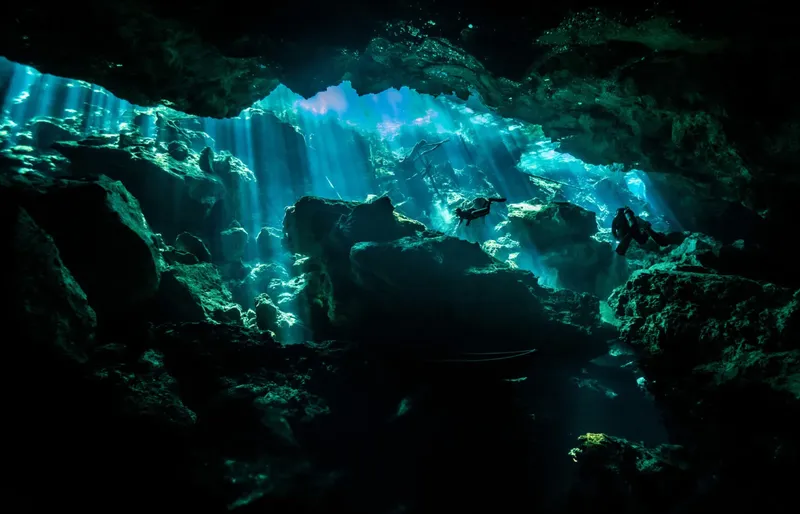 Plongeurs explorant une grotte sous-marine avec des rayons de lumière