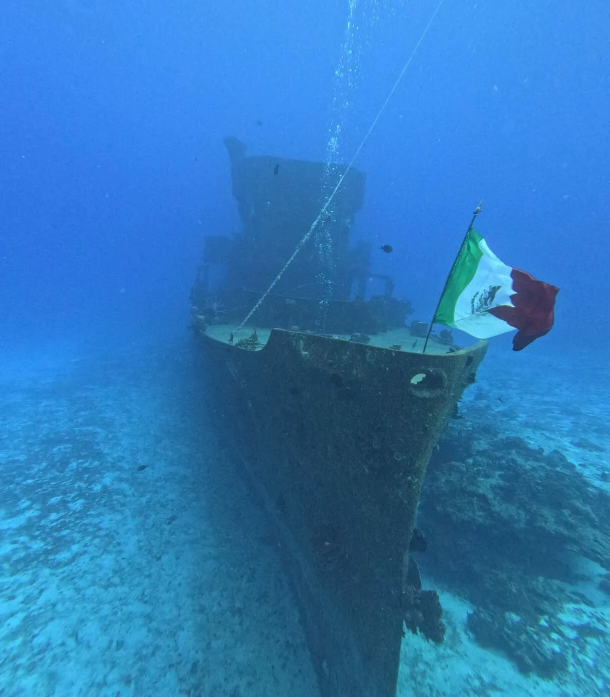 Épave de bateau immergée avec un drapeau mexicain flottant sous l'eau