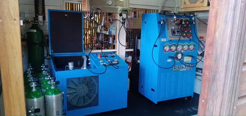 Compresseurs bleus et bouteilles d'air comprimé dans un atelier sombre