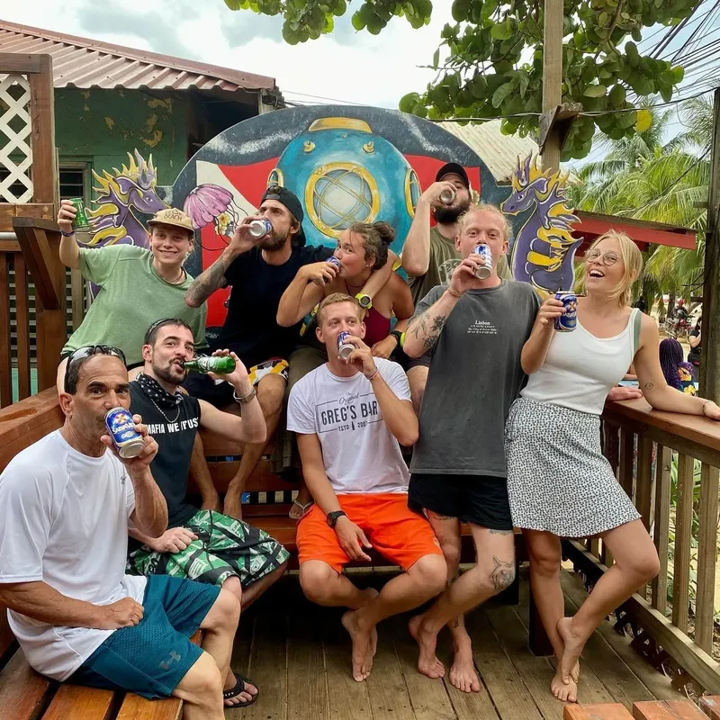 Groupe de personnes souriantes tenant des bières dans un cadre tropical