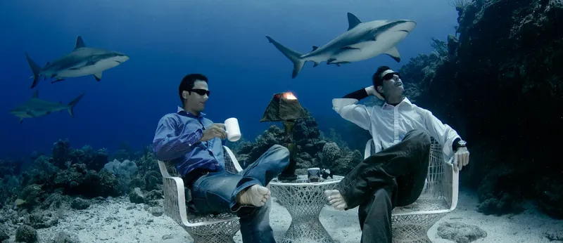 Deux hommes en costume assis sous l'eau avec des requins