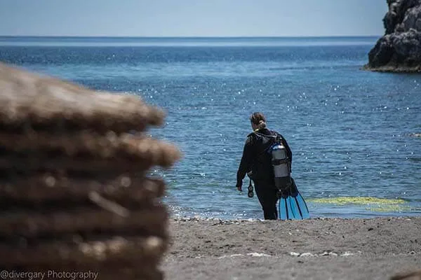 Plongeur sortant de l'eau avec son équipement sur une plage