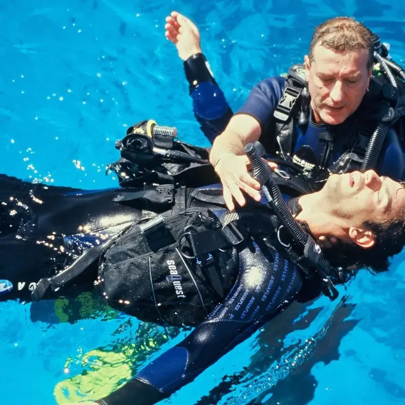 Deux plongeurs en combinaison flottent dans une eau turquoise claire
