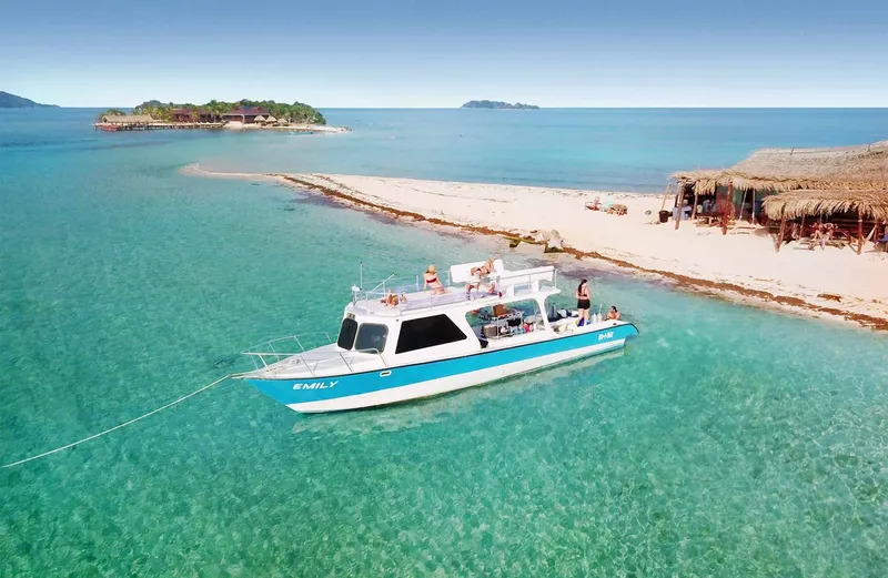 Bateau de plongée turquoise avec des passagers naviguant vers une île
