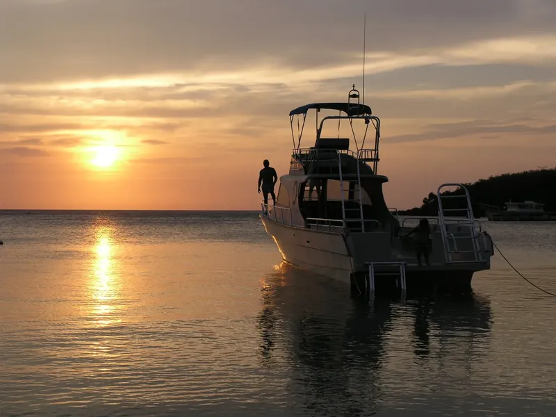Silhouette d'un plongeur sur l'arrière d'un bateau au coucher du soleil
