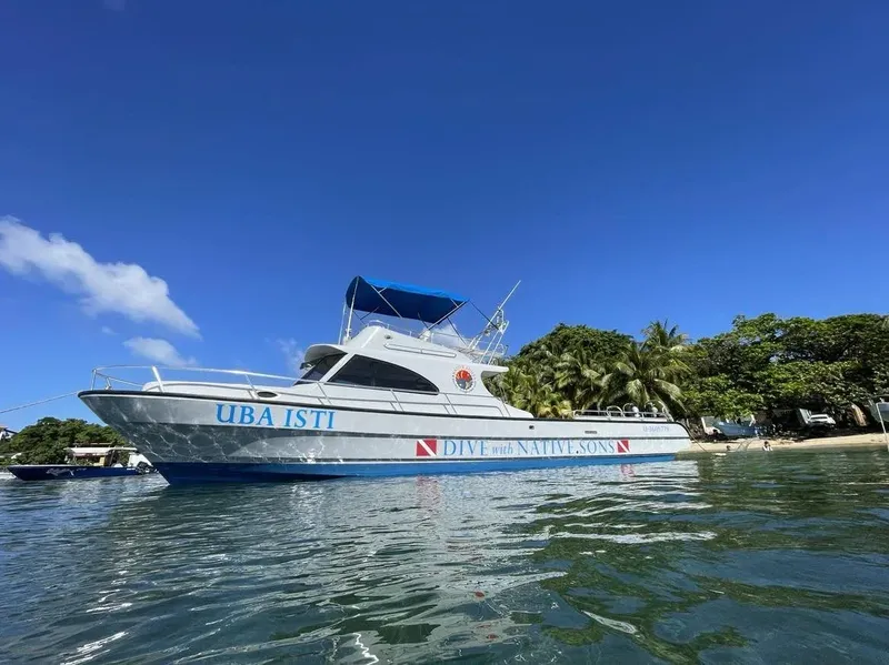 Bateau de plongée bleu et blanc amarré sur une eau turquoise claire