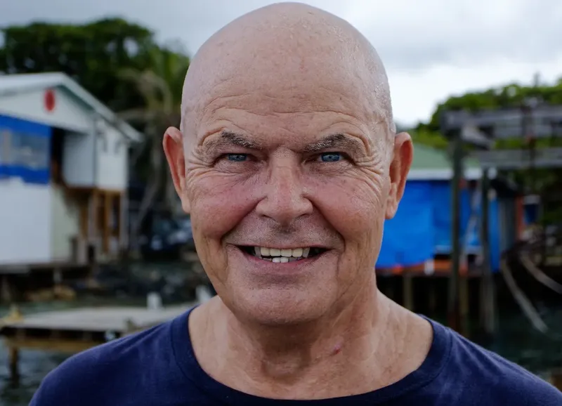 Portrait d'un homme souriant sur un fond de maisons colorées