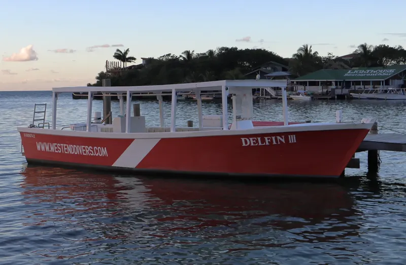 Bateau rouge amarré à un ponton avec un site de restauration en arrière-plan