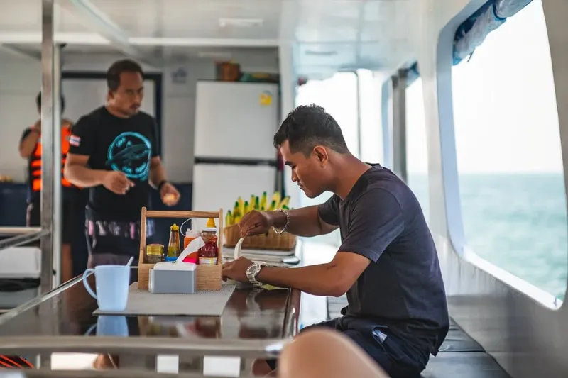 Deux hommes à bord d'un bateau, préparant ou prenant le petit-déjeuner