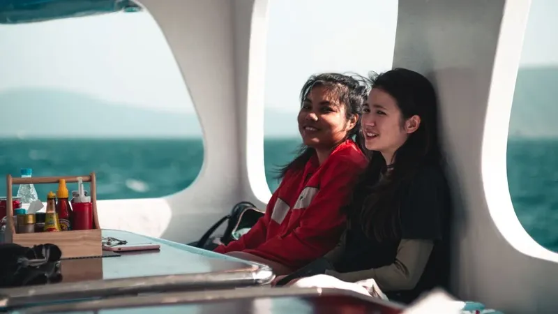 Deux femmes souriantes sur un bateau, regardant vers l'horizon marin
