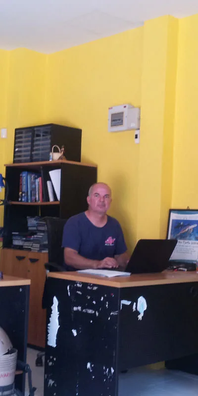 Un homme chauve assis à un bureau dans un local jaune