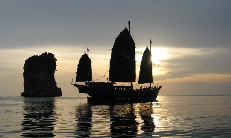 Joncque traditionnelle naviguant au coucher du soleil sur une mer calme