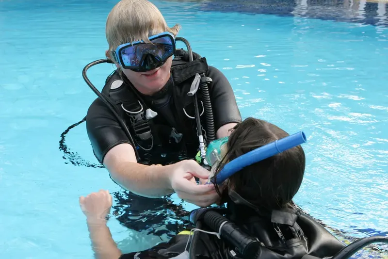 Deux plongeurs en formation dans une piscine, vérification du matériel