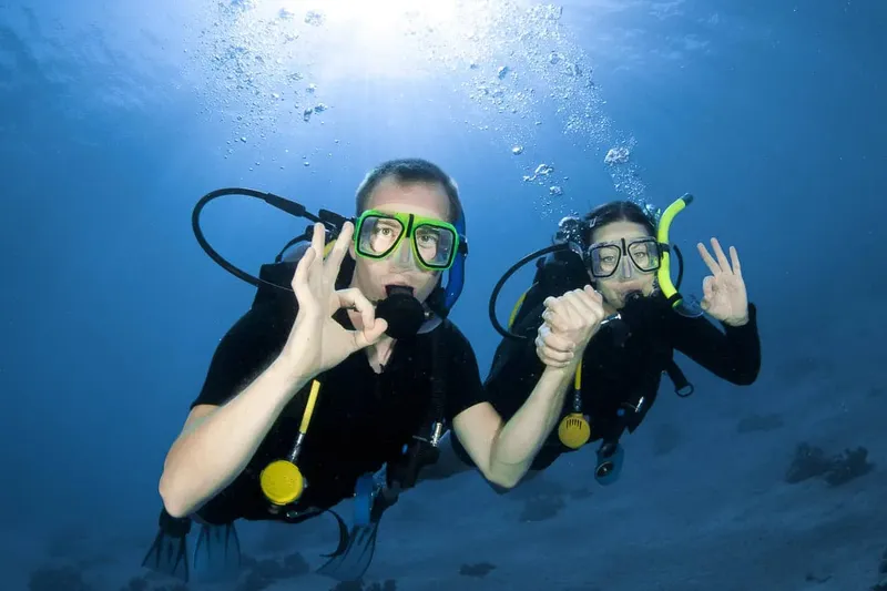 Deux plongeurs souriants font des signes de validation sous l'eau