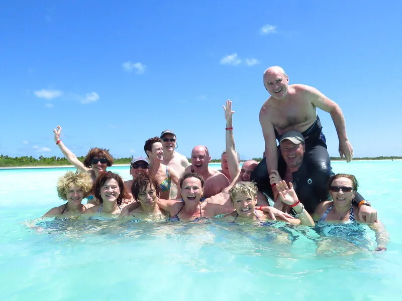 Groupe de personnes souriantes dans une eau turquoise peu profonde