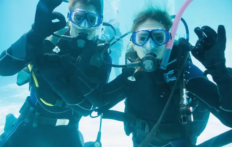 Deux plongeurs souriants avec leur équipement complet sous l'eau