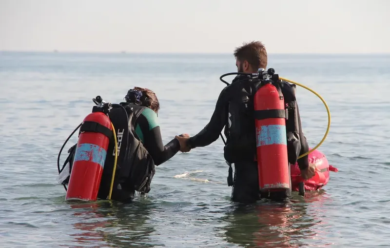 Deux plongeurs en combinaison se tiennent la main dans l'eau