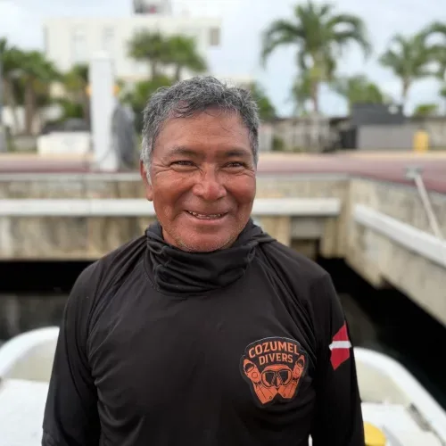 Portrait d'un homme souriant avec un t-shirt de plongée devant un quai