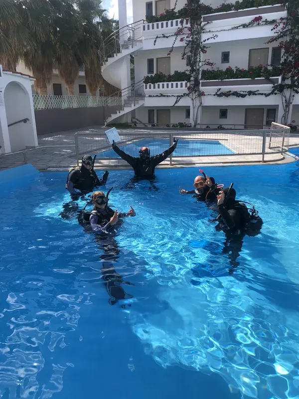 Plongeurs en formation dans une piscine, sourires et signes de validation