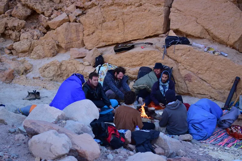 Groupe de personnes assises autour d'un feu de camp au bord de l'eau