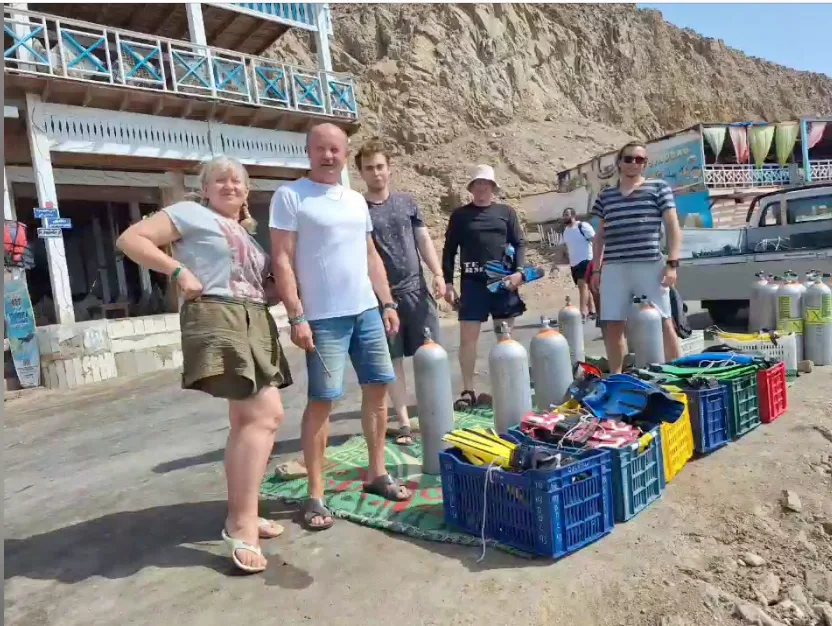 Groupe de plongeurs avec équipement devant un centre de plongée