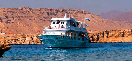 Bateau de plongée en mer avec des passagers et un paysage rocheux
