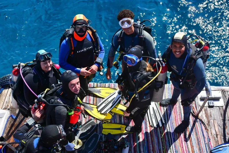 Groupe de plongeurs souriants sur un bateau avec leur équipement