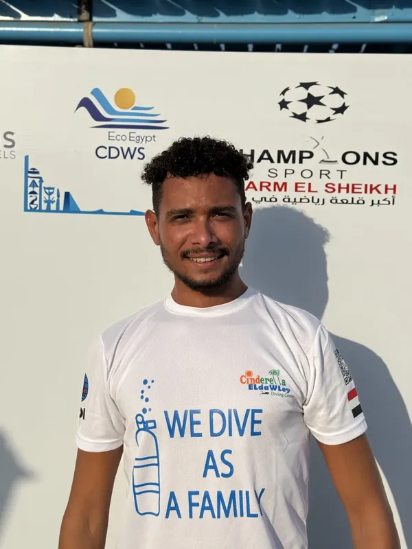 Un homme souriant porte un t-shirt avec un message de plongée