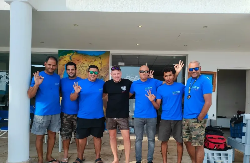 Groupe de personnes souriantes, portant des t-shirts bleus, devant un bâtiment