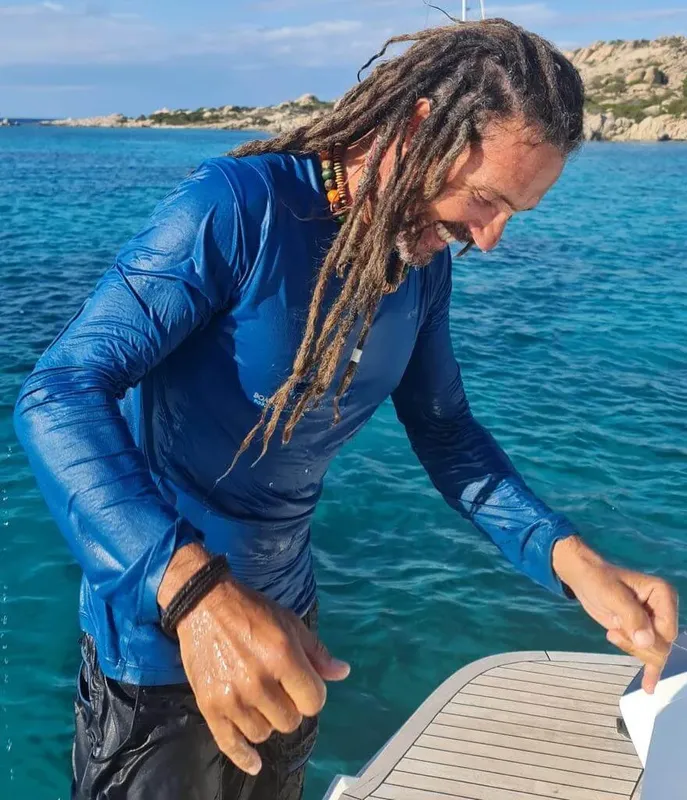 Homme aux dreadlocks sur un bateau, préparant quelque chose près de l'eau