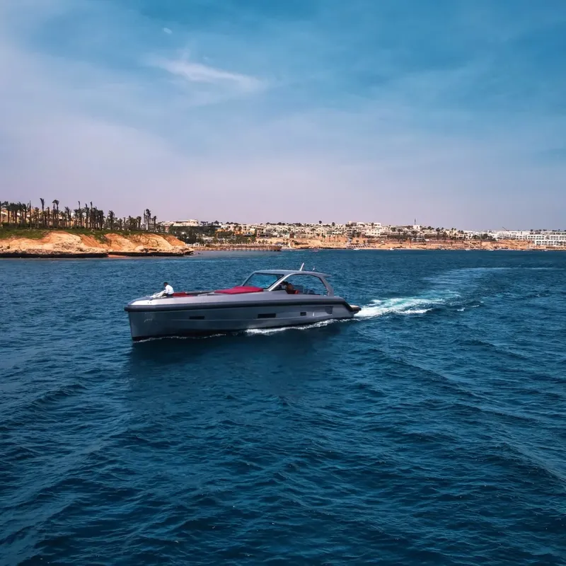 Bateau gris naviguant sur une mer bleue avec une côte rocheuse