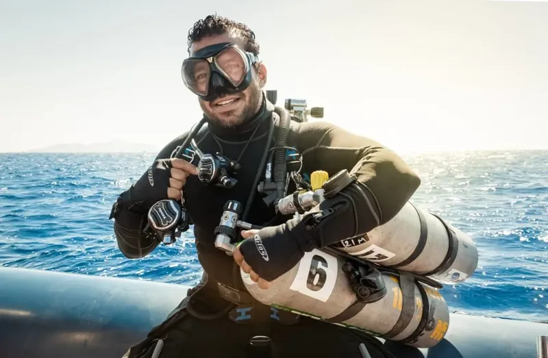 Plongeur souriant avec équipement complet sur un bateau en mer