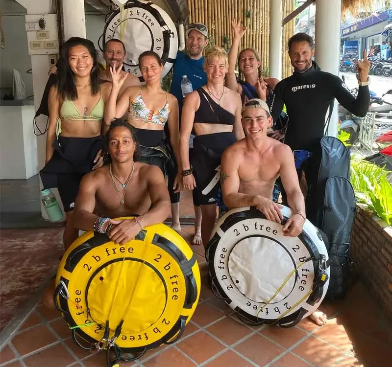 Groupe de plongeurs souriants posant avec du matériel de plongée jaune
