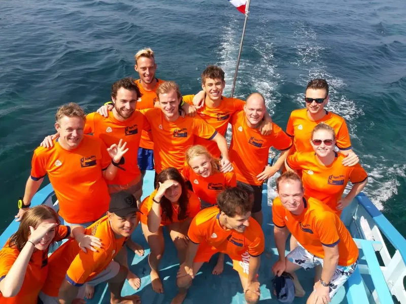 Groupe de plongeurs souriants sur un bateau en mer, journée ensoleillée