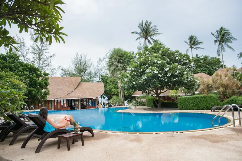 Vue d'une piscine avec des transats et des bâtiments tropicaux