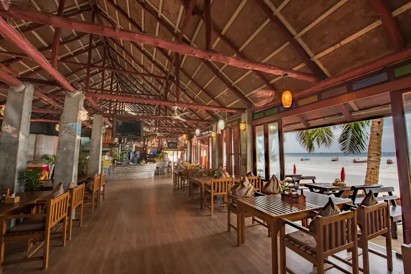 Intérieur d'un restaurant ouvert sur une plage avec tables et bar