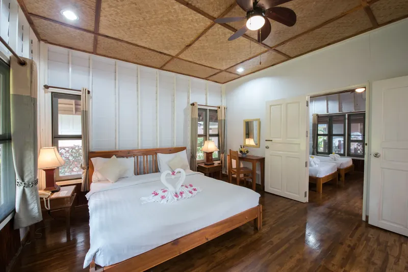 Chambre d'hôtel lumineuse avec lits décorés et mobilier en bois