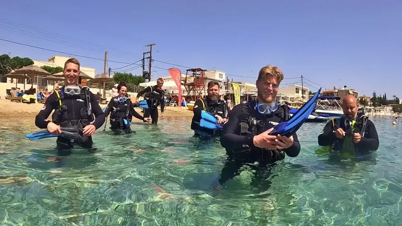 Groupe de plongeurs en combinaison s'apprêtant à entrer dans l'eau