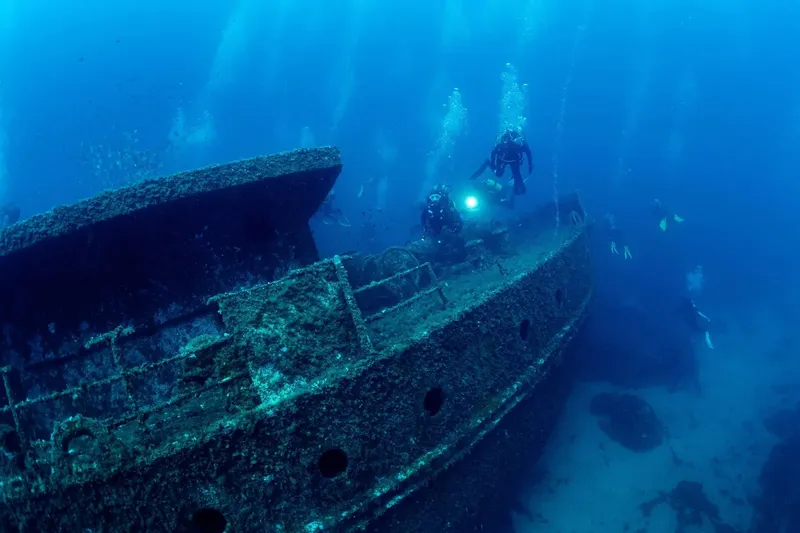 Plongeurs explorent l'épave d'un bateau rouillé en milieu marin