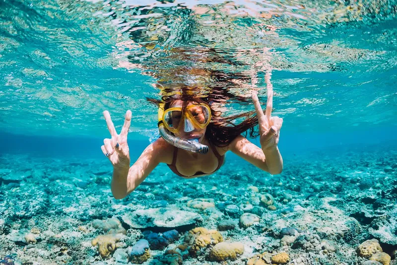 Plongeuse souriante avec masque et signe de la paix sous l'eau
