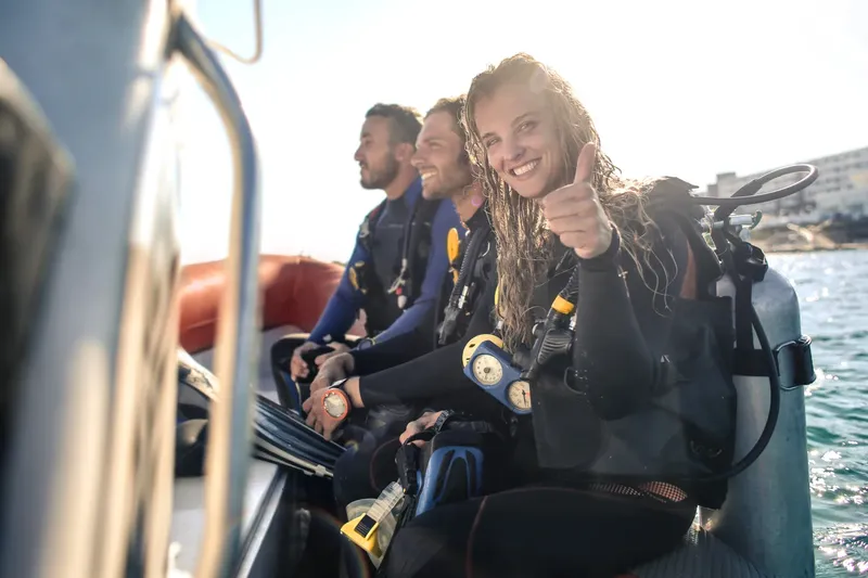 Plongeurs souriants avec équipement complet à bord d'un bateau pneumatique