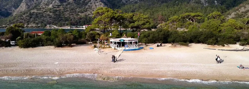Plage de galets avec quelques personnes et un petit bâtiment blanc