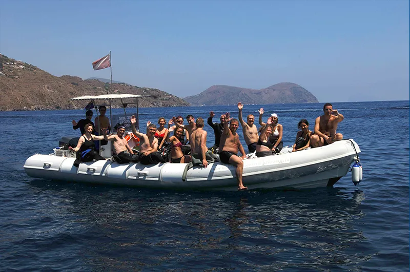 Groupe de plongeurs souriants à bord d'un bateau semi-rigide en mer