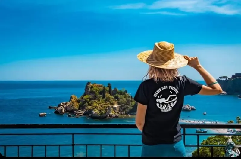 Femme de dos, portant un chapeau, regardant la mer et les ilots