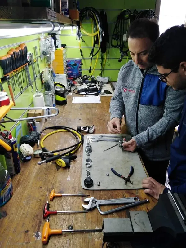 Deux personnes travaillent sur un détendeur de plongée avec des outils