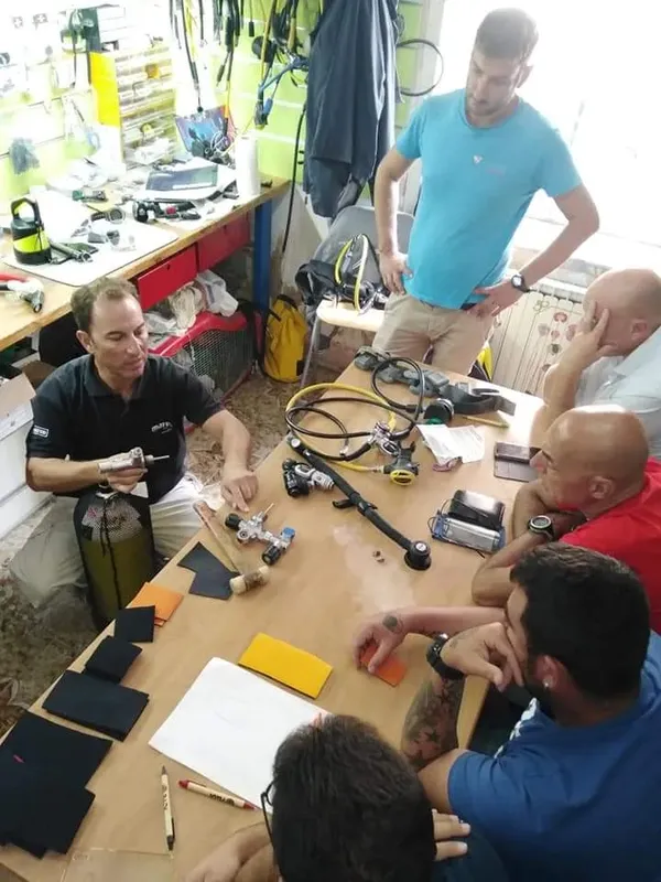 Groupe de personnes autour d'une table avec équipement de plongée