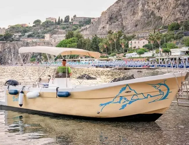 Homme debout sur un bateau beige amarré près d'une plage